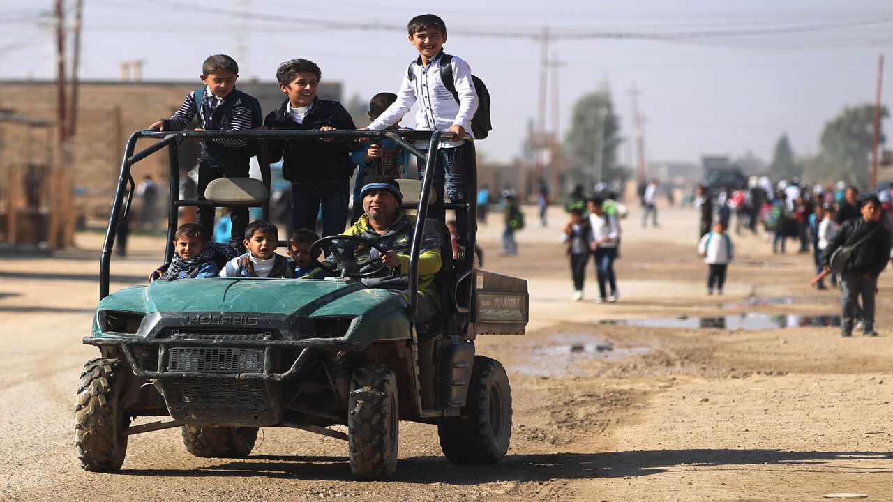 1061347590 A man drives a group of pupils to school in al-Qaim in the Iraqi Anbar province, opposite Albu Kamal in Syria's Deir Ezzor region, on November 13, 2018. - Iraqi troops have reinforced their positions along the porous frontier with neighbouring war-torn Syria, fearing a spillover from clashes there between the Islamic State (IS) group and US-backed forces. (Photo by AHMAD AL-RUBAYE / AFP) (Photo credit should read AHMAD AL-RUBAYE/AFP via Getty Images)