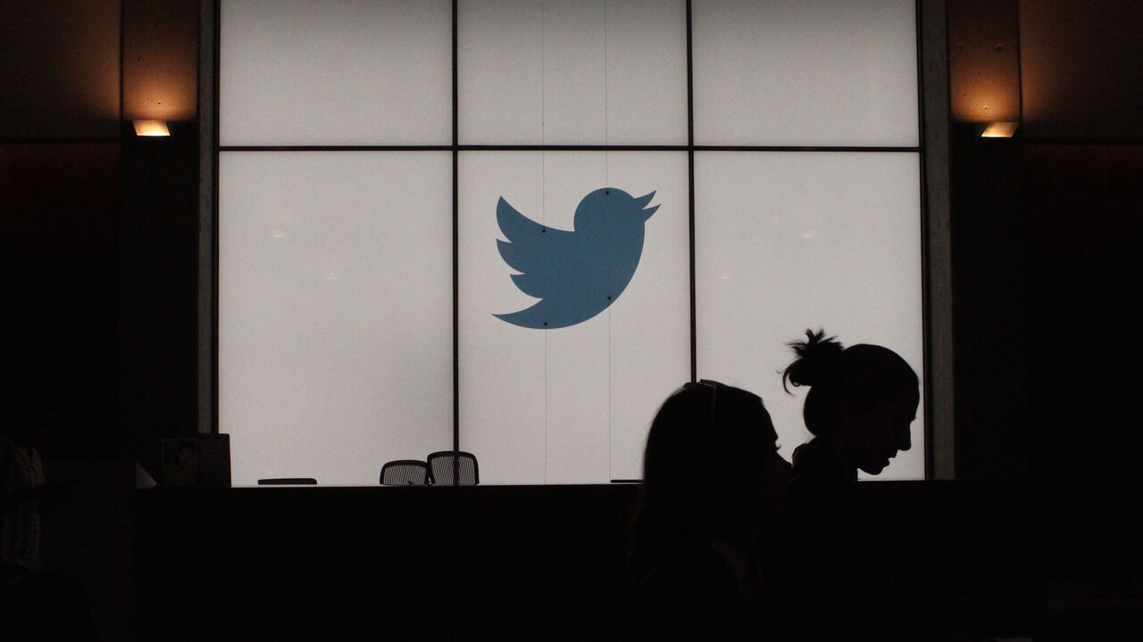 1161582843 Employees walk past a lighted Twitter log as they leave the company's headquarters in San Francisco on August 13, 2019. - Twitter on August 13 said that by the end of the year users will be able to follow a small number of interests the same way they follow people. The feature will be rolled out internationally as the one-to-many messaging platform makes a priority of being an online venue for conversations rather than a pulpit for one-way broadcasting to the masses. (Photo by Glenn CHAPMAN / AFP) (Photo by