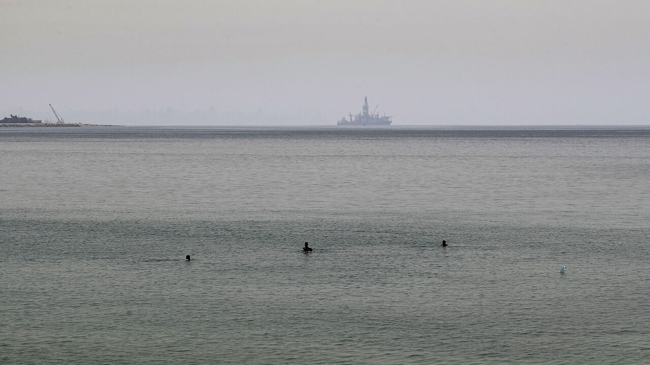 1213955372 The Tungsten Explorer, an off-shore oil and gas exploration drillship, is seen in the background as people bathe in the Mediterranean water off the coast of Jounieh bay, north of Lebanon's capital Beirut, on May 19, 2020, despite beaches being legally closed due to COVID-19 coronavirus restrictions. - Lebanon gradually started lifting a COVID-19 coronavirus lockdown that has compounded its economic crisis despite an uptick in cases that prompted a four-day lockdown. Across the Mediterranean, a seasonal reco