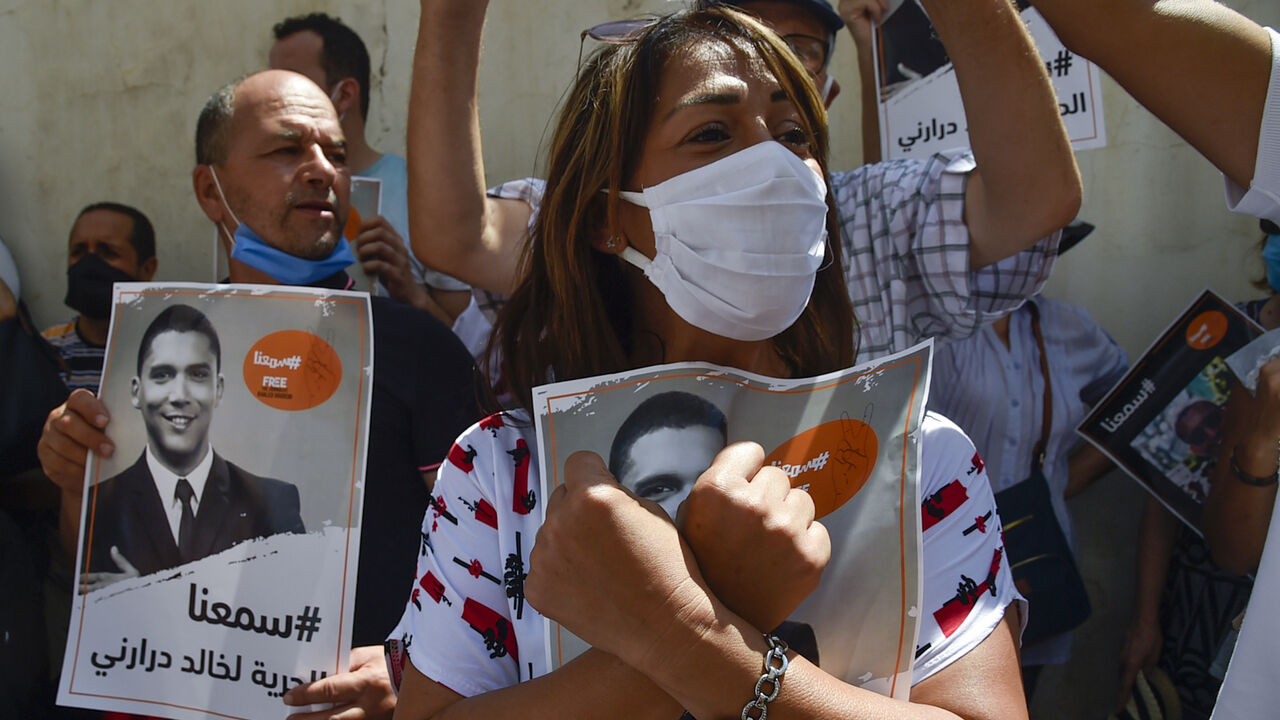 1228181856 Algerian journalists gather in protest to demand the release of their colleague Khaled Drareni (poster), who was sentenced earlier this month to three years in jail for "inciting an unarmed gathering" and "endangering national unity", in the capital Algiers on August 24, 2020. - The Algerian justice system has in recent months increased the court cases and convictions against alleged Hirak militants, opposition politicians, journalists and social media users. (Photo by RYAD KRAMDI / AFP) (Photo by RYAD KRAM