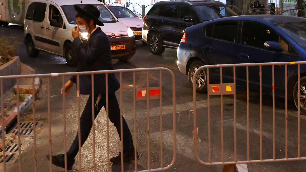 1228404416 An ultra-Orthodox Jewish youth walks past a barrier set up by Israeli police on the road in the religious Israeli city of Bnei Brak, near Tel Aviv, amid measures put in place by Israeli authorities in a bid to stop the spread of Covid-19, on September 8, 2020. - In March, Bnei Brak was an initial "rebel" against the government's coronavirus rules, compelling authorities to deploy soldiers to help police impose containment measures. But after infection rates peaked across the country, Israel on Monday impose