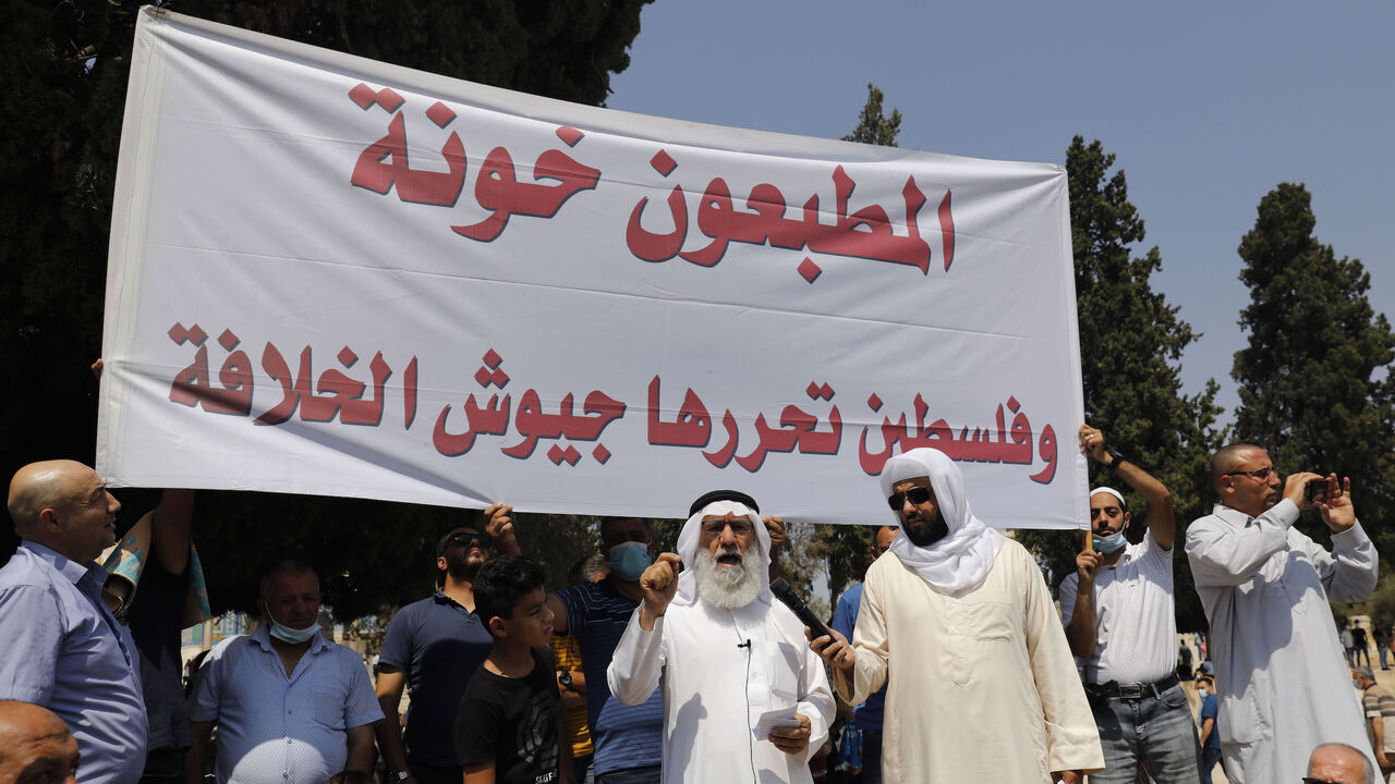 1228572870 Palestinian Muslim worshippers hold a protest sign against the normalisation of ties between Israel and two Arab states, during Friday noon prayers at the al-Aqsa mosque compound in the old city of Jerusalem on September 18, 2020. - Israeli Prime Minister Benjamin Netanyahu and the foreign ministers of Bahrain and the United Arab Emirates signed agreements establishing full diplomatic ties at a ceremony at the White House. (Photo by Ahmad GHARABLI / AFP) (Photo by AHMAD GHARABLI/AFP via Getty Images)
