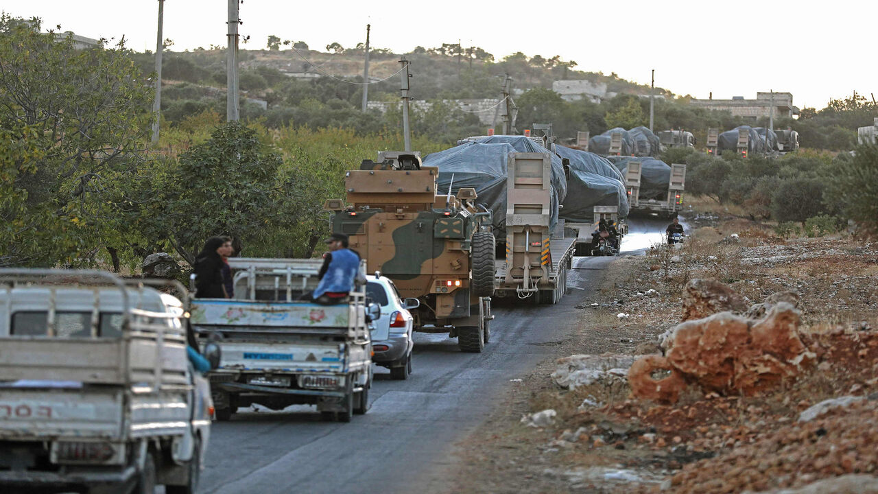 1229183869 Civilians drive along a road behind a Turkish military convoy through the village of Iblin, near Ariha in Syria's rebel-held northwestern Idlib province on October 20, 2020 after Turkish forces vacated the Morek post in Hama's countryside. - Turkey started withdrawing from one of its largest outposts in northwest Syria encircled for the past year by Syrian regime forces, a war monitor and a pro-Ankara rebel commander said. The outpost in Morek is Turkey's largest in the northwest province of Hama, which is