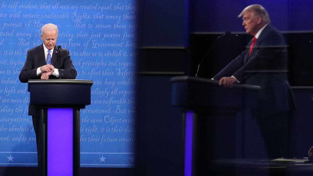 1281738381 NASHVILLE, TENNESSEE - OCTOBER 22: Democratic presidential nominee Joe Biden checks his watch during the final presidential debate against U.S. President Donald Trump (shown in reflection) at Belmont University on October 22, 2020 in Nashville, Tennessee. This is the last debate between the two candidates before the election on November 3. (Photo by Chip Somodevilla/Getty Images)