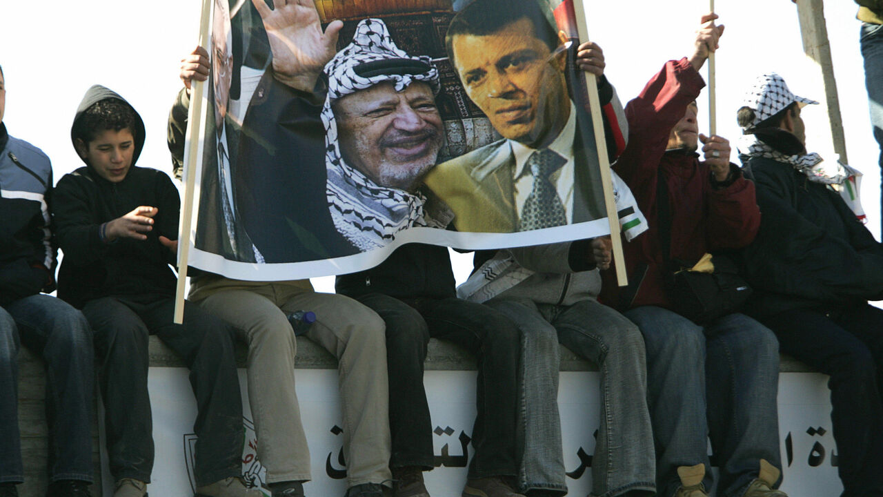 72977062 RAMALLAH, -: Palestinians hold a banner showing late Palestinian leader Yasser Arafat (L) and Fatah MP Mohammed Dahlan during a rally in the West Bank city of Ramallah 11 January 2007, to mark the 42nd anniversary of the Fatah movement. Thousands of flag-waving chanting supporters of Palestinian president Mahmud Abbas's Fatah party poured into central Ramallah for a second rally in less than a week aimed at staging a show of force agains the ruling Hamas movement. AFP PHOTO/PEDRO UGARTE (Photo credit shou