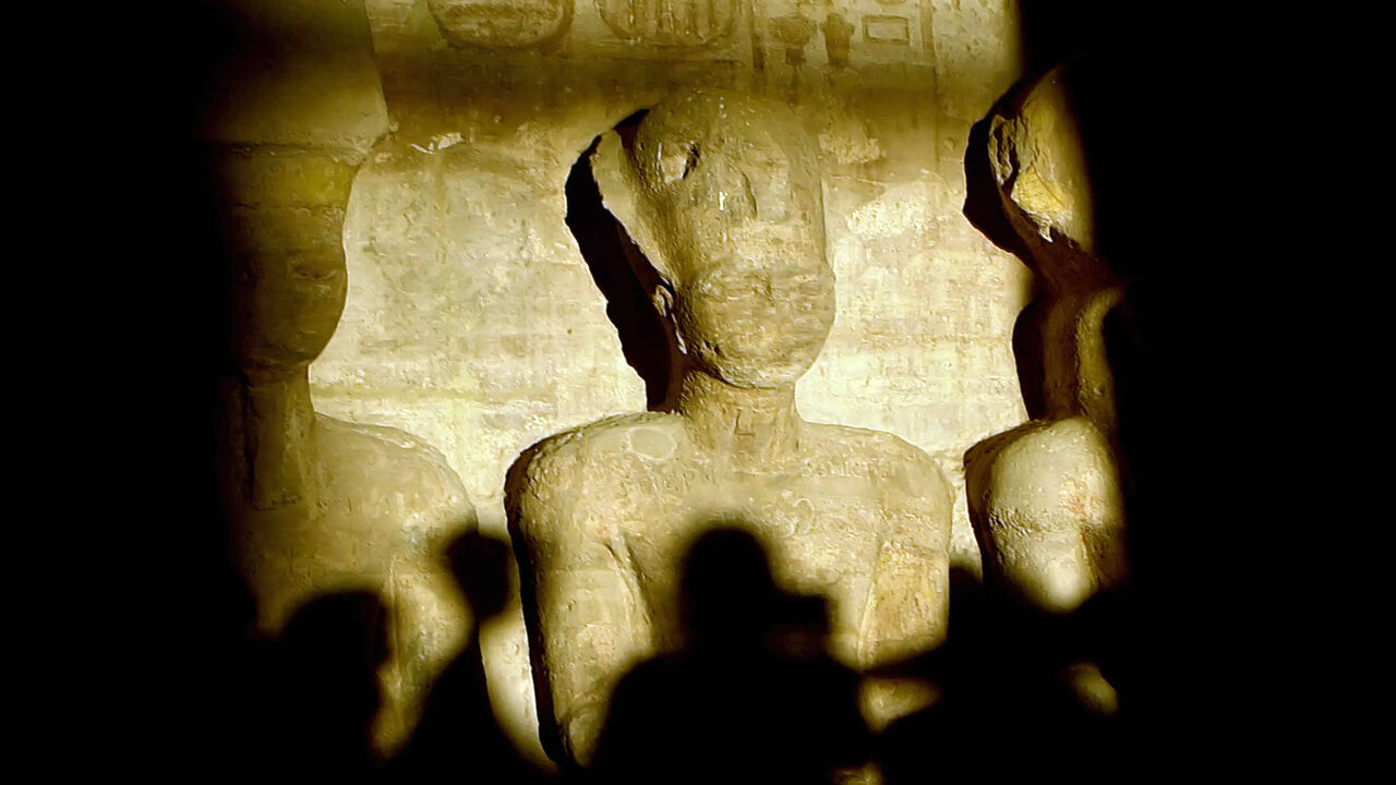 77440857 A picture taken in 2002 shows tourists casting their shadows as a ray of light illuminates the statue of Ramses II inside the temple of Abu Simbel, south of Aswan, in upper Egypt. More than 2500 tourists witnessed 22 October 2007 the sun illuminating the inner sanctuary, which happens only twice a year with a wide belief among archaeologists that the two days mark Ramsis II's birthday and day of coronation. AFP PHOTO/KHALED DESOUKI (Photo credit should read KHALED DESOUKI/AFP via Getty Images)