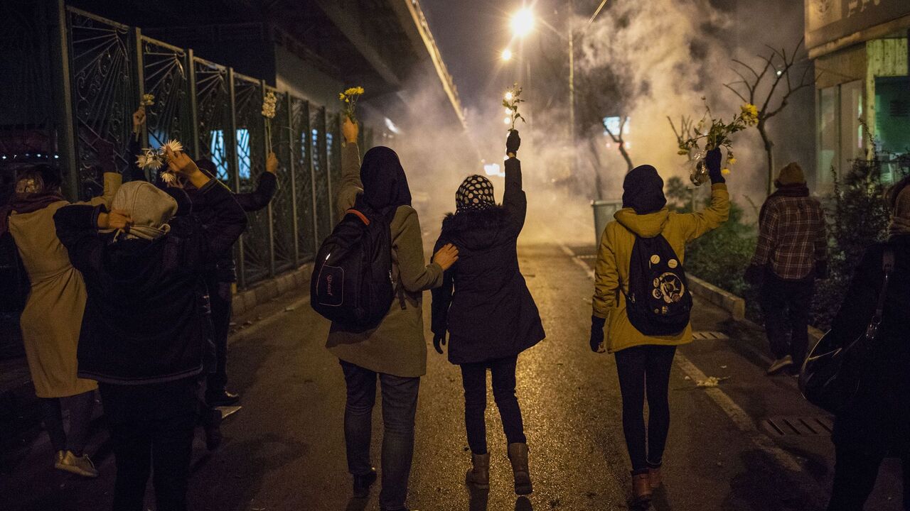 1193458412 Iranian protesters hold flowers as riot police fire tear gas during a demonstration in front of Tehran's Amir Kabir University on January 11, 2020. - Demonstrations broke out for a second night in a row after Iran admitted to having shot down a Ukrainian passenger jet by mistake on January 8, killing all 176 people on board. (Photo by STR / AFP) (Photo by STR/AFP via Getty Images)
