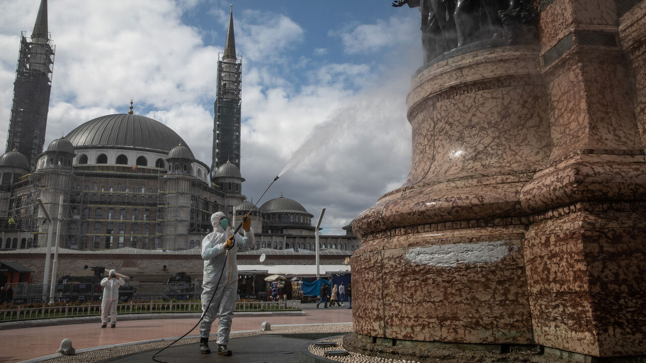 1213221266 ISTANBUL, TURKEY - MARCH 18: An employee from Istanbul Municipality disinfects the Taksim Republic Statue in Taksim square to prevent the spread of the COVID-19, coronavirus on March 18, 2020 in Istanbul, Turkey. Turkey has confirmed one death and ninety eight positive cases of the coronavirus and officials continue to implement steps to contain the spread of the virus with the Interior Ministry announcing cafes, cinemas, restaurants, shish-a cafes, bars and gyms will close adding to schools, universities