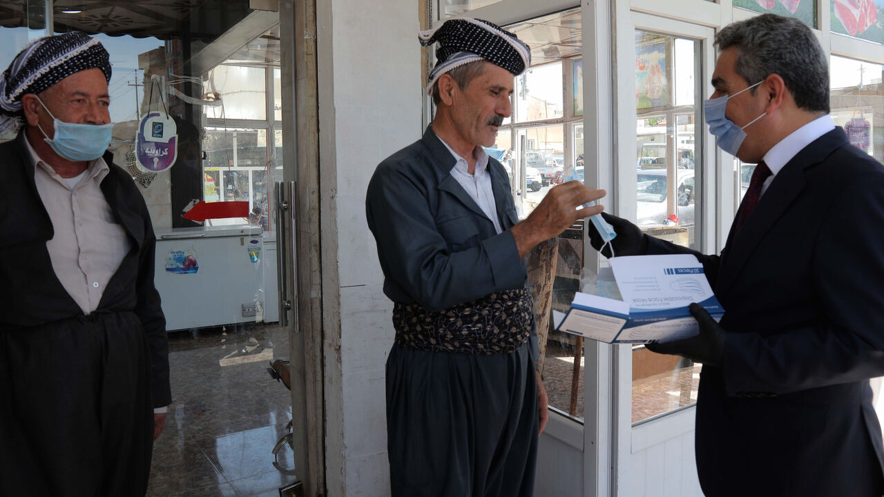 1217494110 Firsat Sofi (R), the governor of Arbil, gives mask to people to protect themselves against the coronavirus COVID-19, on June 4, 2020 in Arbil, the capital of the autonomous Kurdish region of northern Iraq. (Photo by SAFIN HAMED / AFP) (Photo by SAFIN HAMED/AFP via Getty Images)