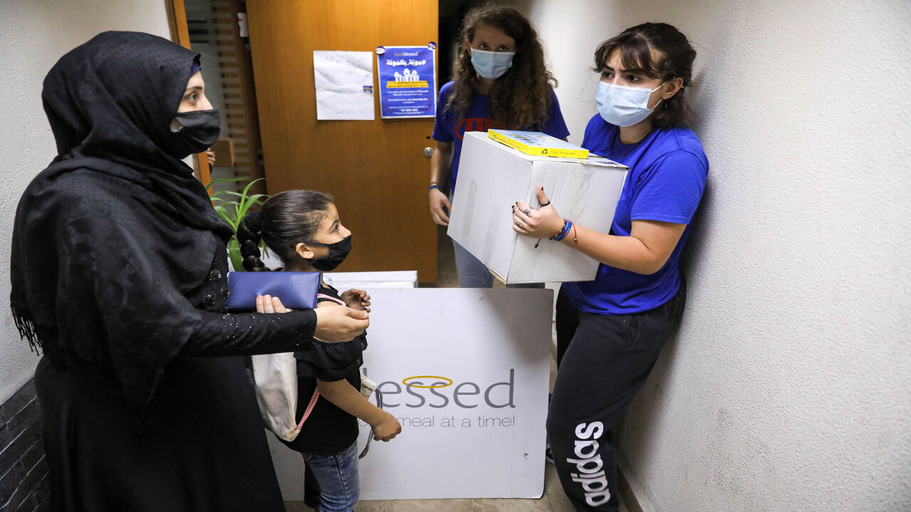 1227997911 People arrive to receive food aid packages from workers, mask-clad due to the COVID-19 coronavirus pandemic, at the Food Blessed NGO's centre in Lebanon's capital Beirut on July 28, 2020. - Amid Lebanon's worst economic crisis since the 1975-1990 civil war, food aid has become a lifeline even for the once relatively affluent middle class. Lebanon's economy has collapsed in recent months, with the local currency plummeting against the dollar, businesses closing en masse and poverty soaring at the same alarmi