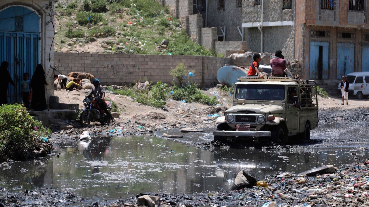 1228597351 A jeep drives in a street flooded with open sewers and covered with scattered rubbish in Yemen's third city of Taez, on September 19, 2020. - Human Rights Watch warned of "deadly consequences" as a result of the obstruction of aid in war-torn Yemen, where the humanitarian effort has already been badly hit by the coronavirus crisis. Interviews with 35 humanitarian workers, 10 donor officials and 10 Yemeni health workers revealed a complex web of restrictions that hinder the flow of aid. (Photo by AHMAD AL-BA