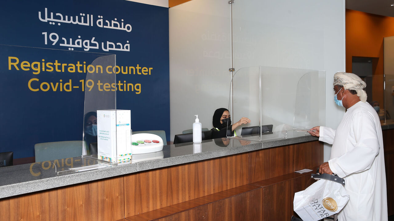 1228823349 A passenger, wearing a protective face mask due to the Covid-19 pandemic, checks-in at the testing counter at the Muscat international airport in the Omani capital on October 1, 2020. (Photo by MOHAMMED MAHJOUB / AFP) (Photo by MOHAMMED MAHJOUB/AFP via Getty Images)