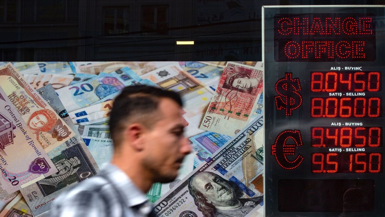 1229294062 A man walks past an information screen displaying rates in front of an exchange office in Istanbul, on October 26, 2020 as Turkey's lira set a new record low against the US dollar. - Turkey's lira was trading at 8.03 against the dollar at around 0730 GMT, suffering a loss of nearly one percent since the beginning of the day. The Turkish currency also recorded its lowest level against the euro, trading near 9.52. (Photo by Yasin AKGUL / AFP) (Photo by YASIN AKGUL/AFP via Getty Images)