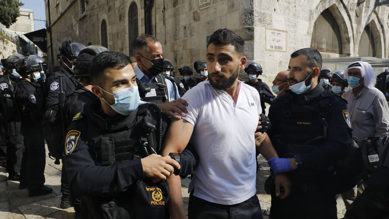 1229357297 Israeli forces arrest a man following a protest against comments by French President Emmanuel Macron defending cartoons of the Prophet Mohammed, outside the al-Aqsa mosque compound, in the Old City of Jerusalem, on October 30, 2020. (Photo by Ahmad GHARABLI / AFP) (Photo by AHMAD GHARABLI/AFP via Getty Images)