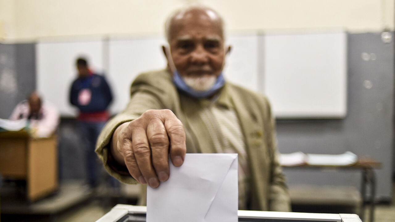 1229403141 A man casts his vote just before polls close at a polling station in Algeria's capital Algiers on November 1, 2020, during a referendum on a revised constitution. - Algerians on November 1 largely snubbed a poll on a revised constitution the regime hoped would neutralise a protest movement which at its peak last year swept long-time president Abdelaziz Bouteflika from power. With the "yes" camp almost certain to win, the only real question mark was over participation in a vote also seen as a bid to bolster