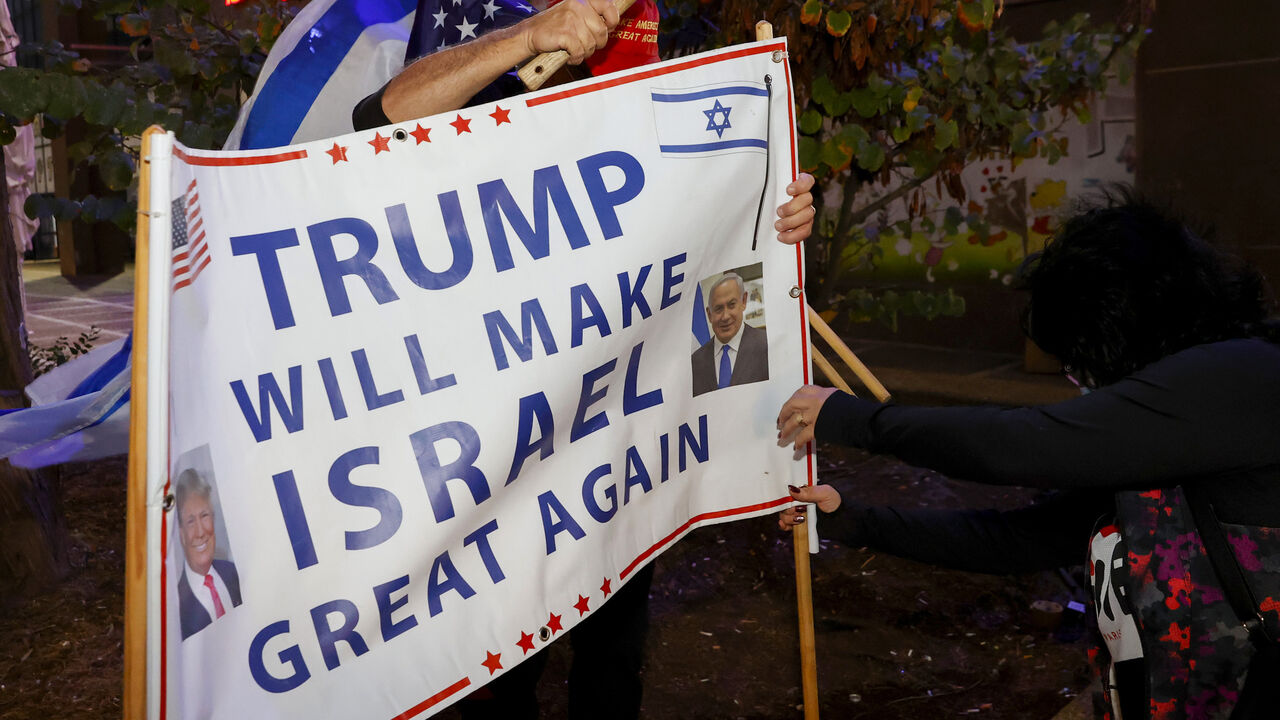 1229439493 Israeli supporters of US President Donald Trump hammer a sign into the ground during a rally in the northern Israeli city of Karmiel near Haifa on November 3, 2020, to express their support for him during the US presidential election. (Photo by JACK GUEZ / AFP) (Photo by JACK GUEZ/AFP via Getty Images)