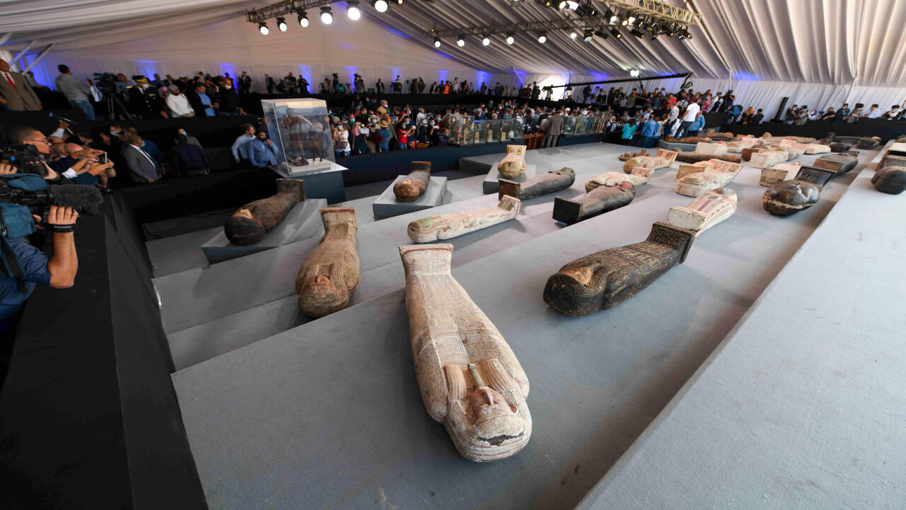 1229614130 A picture shows wooden sarcophagi on display during the unveiling of an ancient treasure trove of more than a 100 intact sarcophagi, at the Saqqara necropolis 30 kms south of the Egyptian capital Cairo, on November 14, 2020. - Egypt announced the discovery of an ancient treasure trove of more than a 100 intact sarcophagi, the largest such find this year. The sealed wooden coffins, unveiled on site amid fanfare, belonged to top officials of the Late Period and the Ptolemaic period of ancient Egypt. They were
