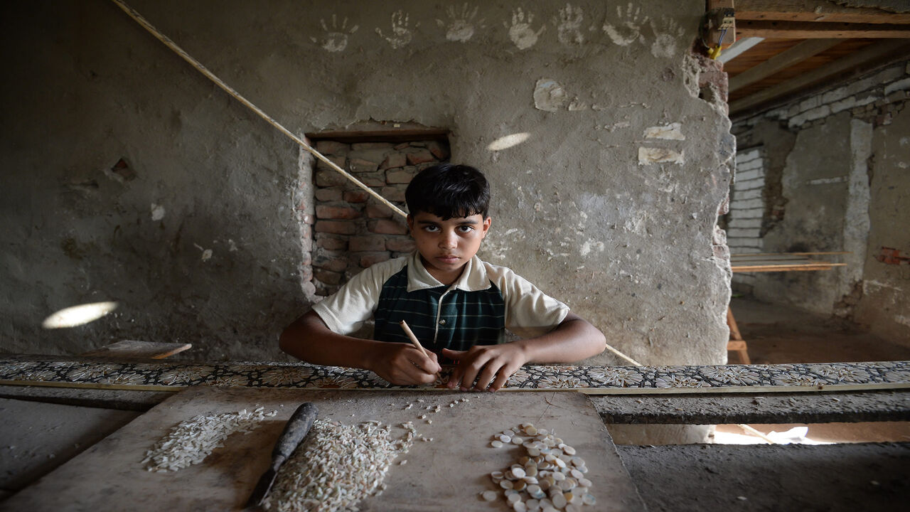 999417798 Egyptian boy Abbas Ali, 12, looks on as he works at a shop specialised in seashell wood inlays in the Saqyat al-Manqadi village in the Egyptian Nile Delta province of al-Minufiyah, on July 7, 2018. (Photo by Mohamed el-Shahed / AFP) (Photo credit should read MOHAMED EL-SHAHED/AFP via Getty Images)