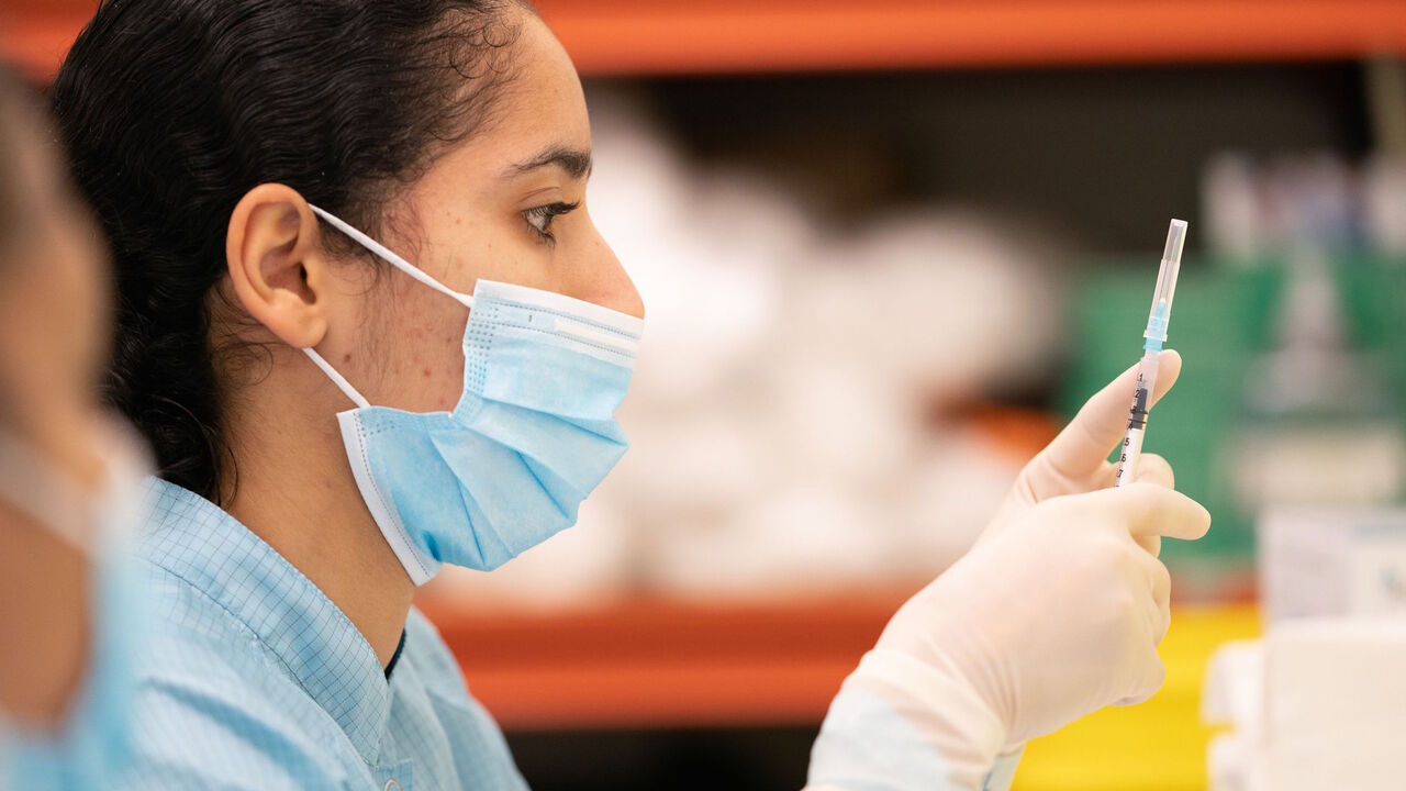 1230012106 A medical professional prepares a syringe with a dose of the Pfizer/BioNTech Covid-19 vaccine, before it is administered to a patient at Croydon University Hospital in south London on December 8, 2020. - Britain on December 8 hailed a turning point in the fight against the coronavirus pandemic, as it begins the biggest vaccination programme in the country's history with a new Covid-19 jab. (Photo by Dan CHARITY / POOL / AFP) (Photo by DAN CHARITY/POOL/AFP via Getty Images)