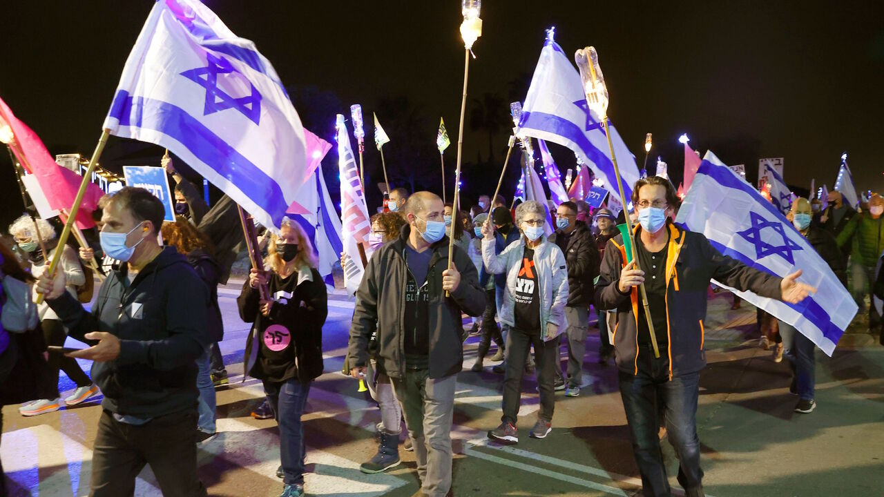 1230089967 Israeli protesters gather with national flags during a protest against Israeli Prime Minister Benjamin Netanyahu near his private home in the coastal town of Caesarea in northern Israel, on December 12, 2020. (Photo by JACK GUEZ / AFP) (Photo by JACK GUEZ/AFP via Getty Images)