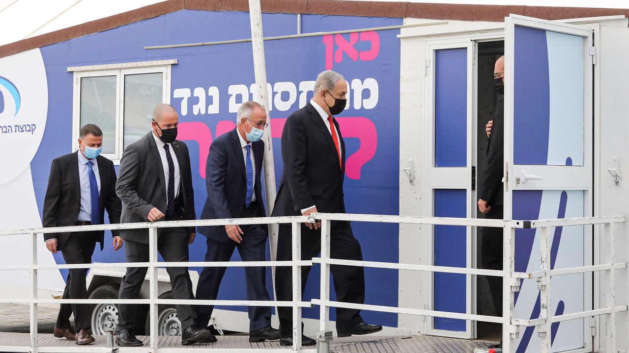 1230099370 Israeli Prime Minister Benjamin Netanyahu (R) and Health Minister Yuli Edelstein (L) arrive at the Maccabi Healthcare Services vaccine complex, handling the COVID-19 coronavirus vaccine, in Israel's Mediterranean coastal city of Tel Aviv on December 13, 2020. (Photo by Marc Israel SELLEM / POOL / AFP) (Photo by MARC ISRAEL SELLEM/POOL/AFP via Getty Images)