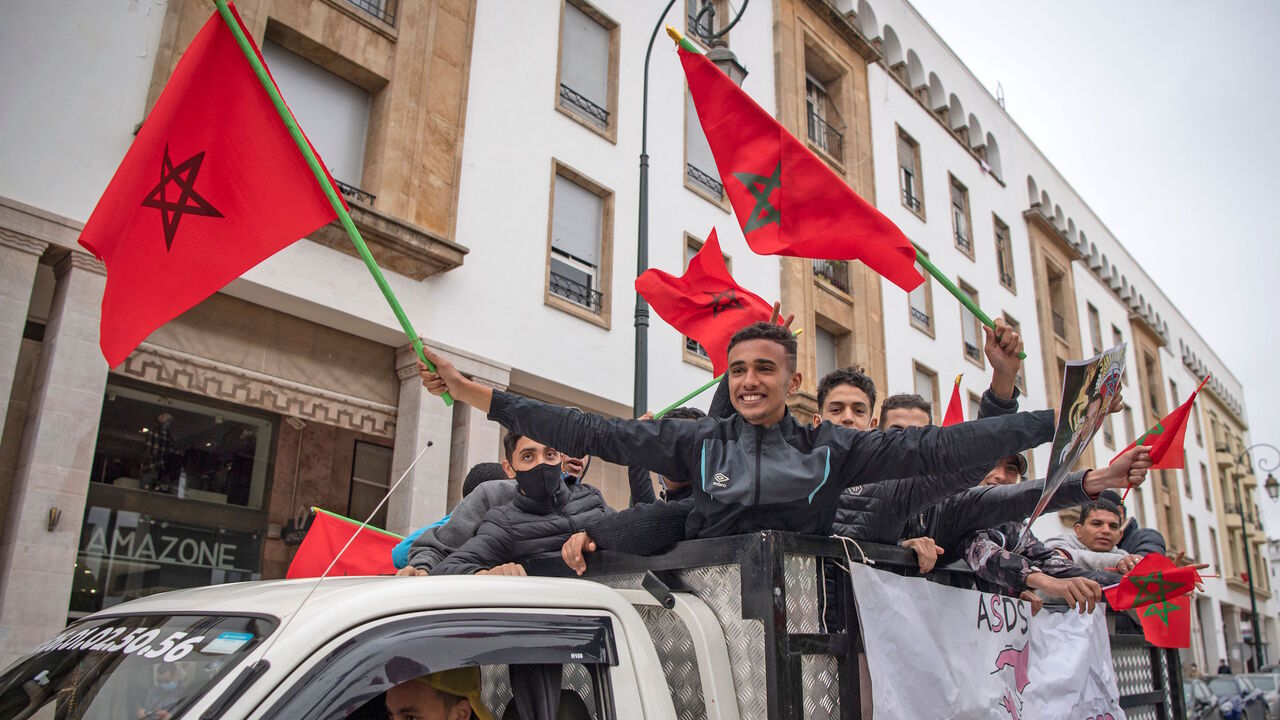 1230108236 Moroccans celebrate in front of the parliament building in Rabat on December 13, 2020, after the US adopted a new official map of Morocco that includes the disputed territory of Western Sahara. - Western Sahara is a disputed and divided former Spanish colony, mostly under Morocco's control, where tensions with the pro-independence Polisario Front have simmered since the 1970s. Morocco became the fourth Arab state this year, after the United Arab Emirates, Bahrain and Sudan, to announce it had agreed to norm