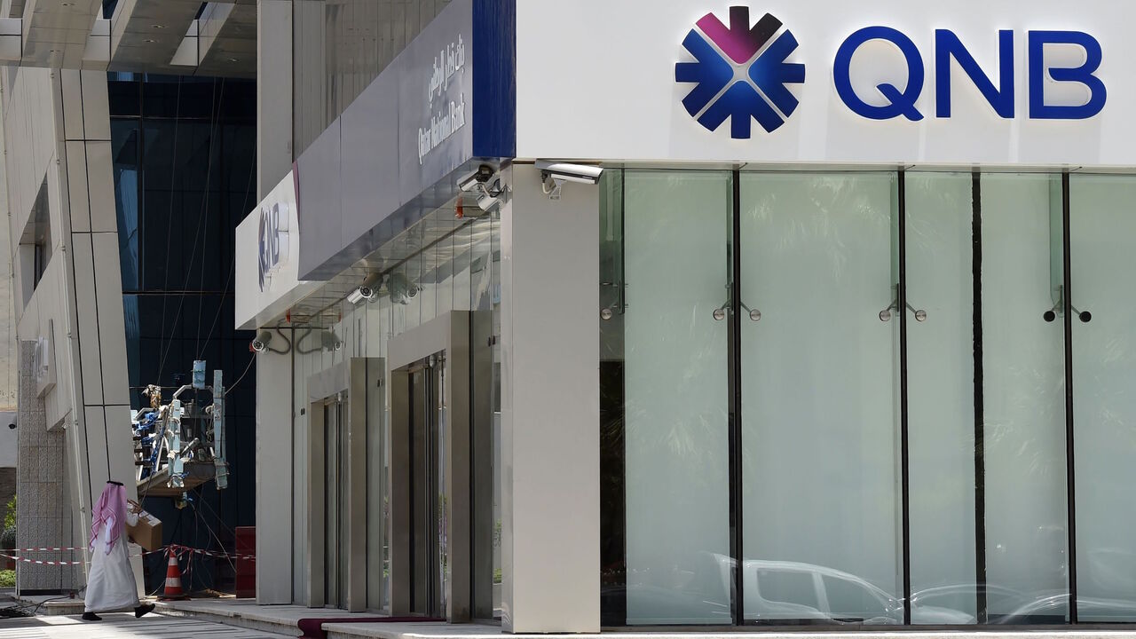692501332 A picture taken on June 5, 2017 shows a man walking past the Qatar National Bank (QNB) branch in the Saudi capital Riyadh, following a severing of relations between major gulf states and gas-rich Qatar. - Arab nations including Saudi Arabia and Egypt cut ties with Qatar accusing it of supporting extremism, in the biggest diplomatic crisis to hit the region in years. (Photo by FAYEZ NURELDINE / AFP) (Photo by FAYEZ NURELDINE/AFP via Getty Images)