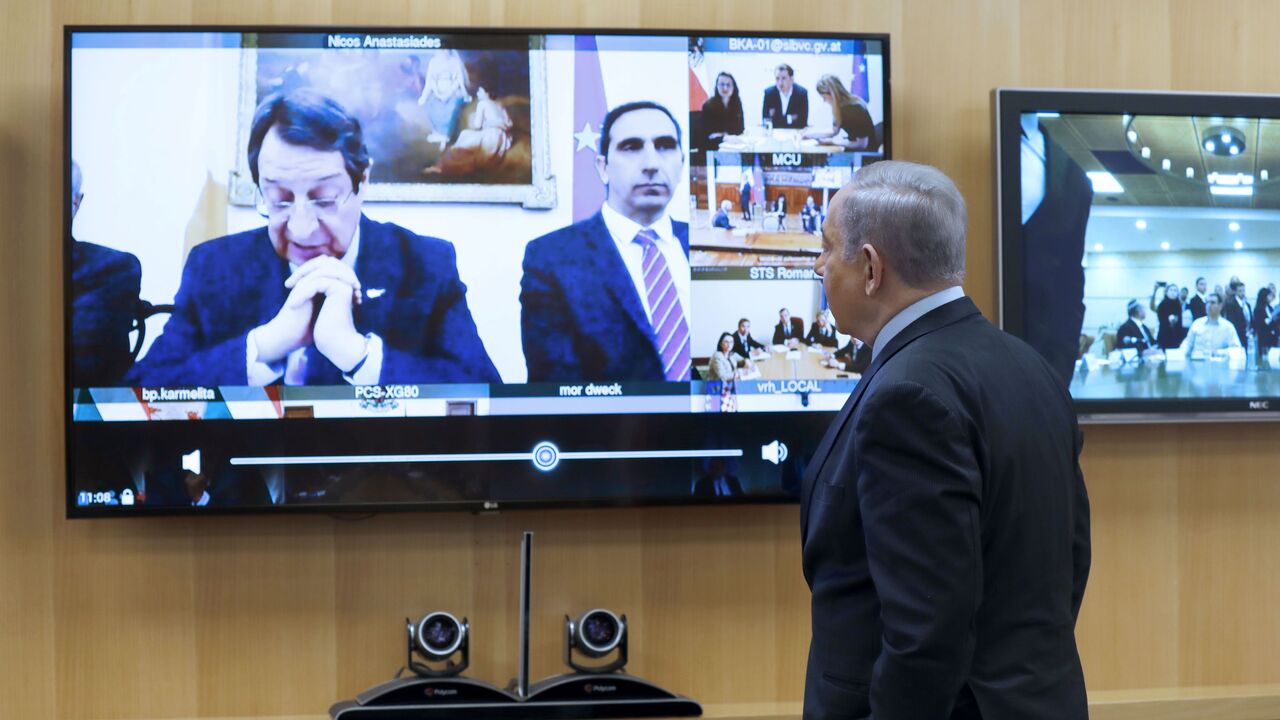 1206147199 Israeli Prime Minister Benjamin Netayahu stands in front of a screen showing the president of Cyprus, Nicos Anastasiades, during a video conference with European leaders in order to discuss challenges and cooperation between various countries in dealing with COVID-19 coronavirus, at the Foreign Ministry in Jerusalem on March 9, 2020. (Photo by MENAHEM KAHANA / AFP) (Photo by MENAHEM KAHANA/AFP via Getty Images)