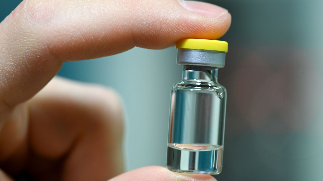 1229763398 DESSAU, GERMANY - NOVEMBER 23: An employee holds an ampoule into which the vaccine is later filled as German Health Minister Jens Spahn tours the lab facilities of vaccine maker IDT Biologika during the second wave of the coronavirus pandemic on November 23, 2020 in Dessau, Germany. IDT Biologika is currently conducting human trials for its potential vaccine against Covid-19. During the company visit, Spahn announced the planned purchase at least five million vaccine doses. (Photo by Hendrik Schmidt-Pool/G