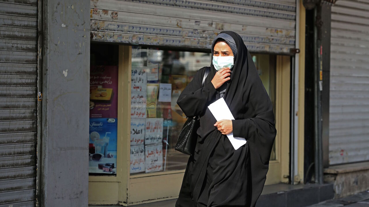 1229867696 A woman wearing a face mask amid the COVID-19 pandemic walks by closed shops in the Iranian capital Tehran, on November 30, 2020. (Photo by ATTA KENARE / AFP) (Photo by ATTA KENARE/AFP via Getty Images)