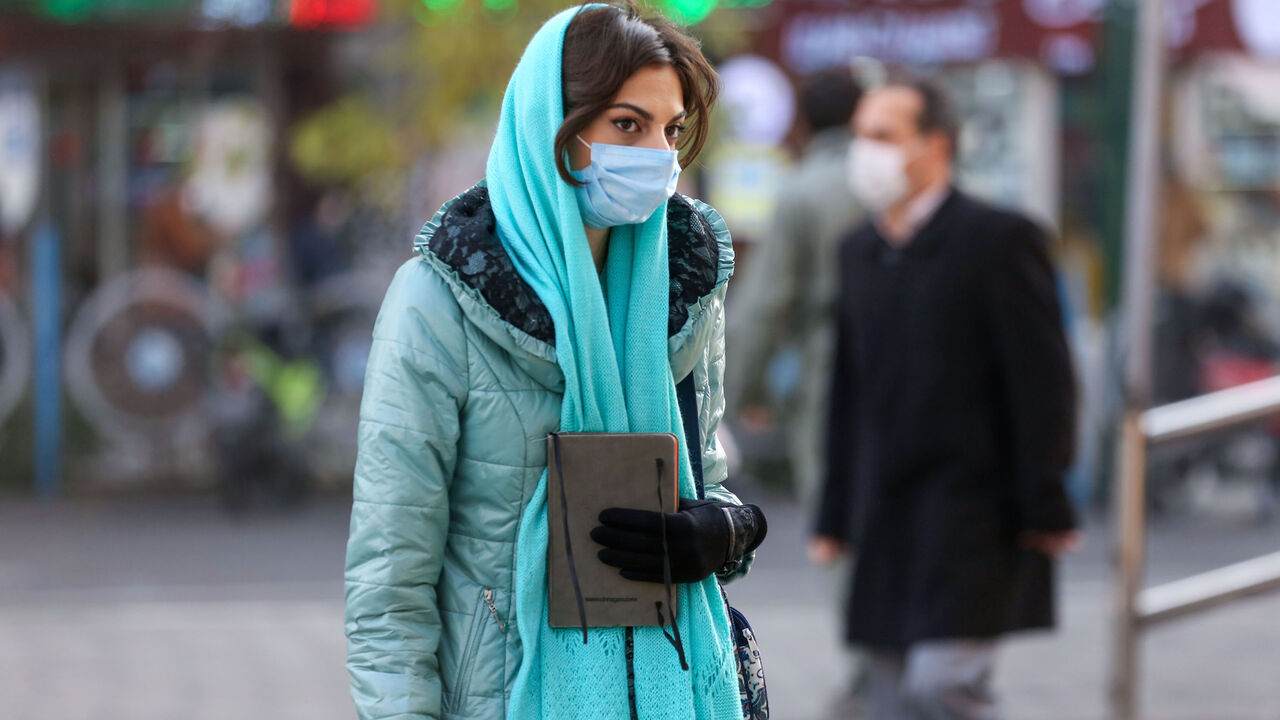 1230355738 An Iranian woman wearing a protective mask amid the COVID-19 pandemic, walks on a street in the capital Tehran, on December 30, 2020. (Photo by ATTA KENARE / AFP) (Photo by ATTA KENARE/AFP via Getty Images)