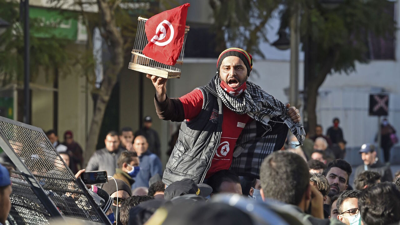 1230672998 A Tunisian protester lifts a flag-clad birdcage during an anti-government demonstration on the Habib Bourguiba avenue in the capital Tunis, on January 19, 2021. - Tunisia braced for further protests after hundreds were arrested in four nights of street clashes between riot police and disaffected youths in cities across the North African country. (Photo by FETHI BELAID / AFP) (Photo by FETHI BELAID/AFP via Getty Images)