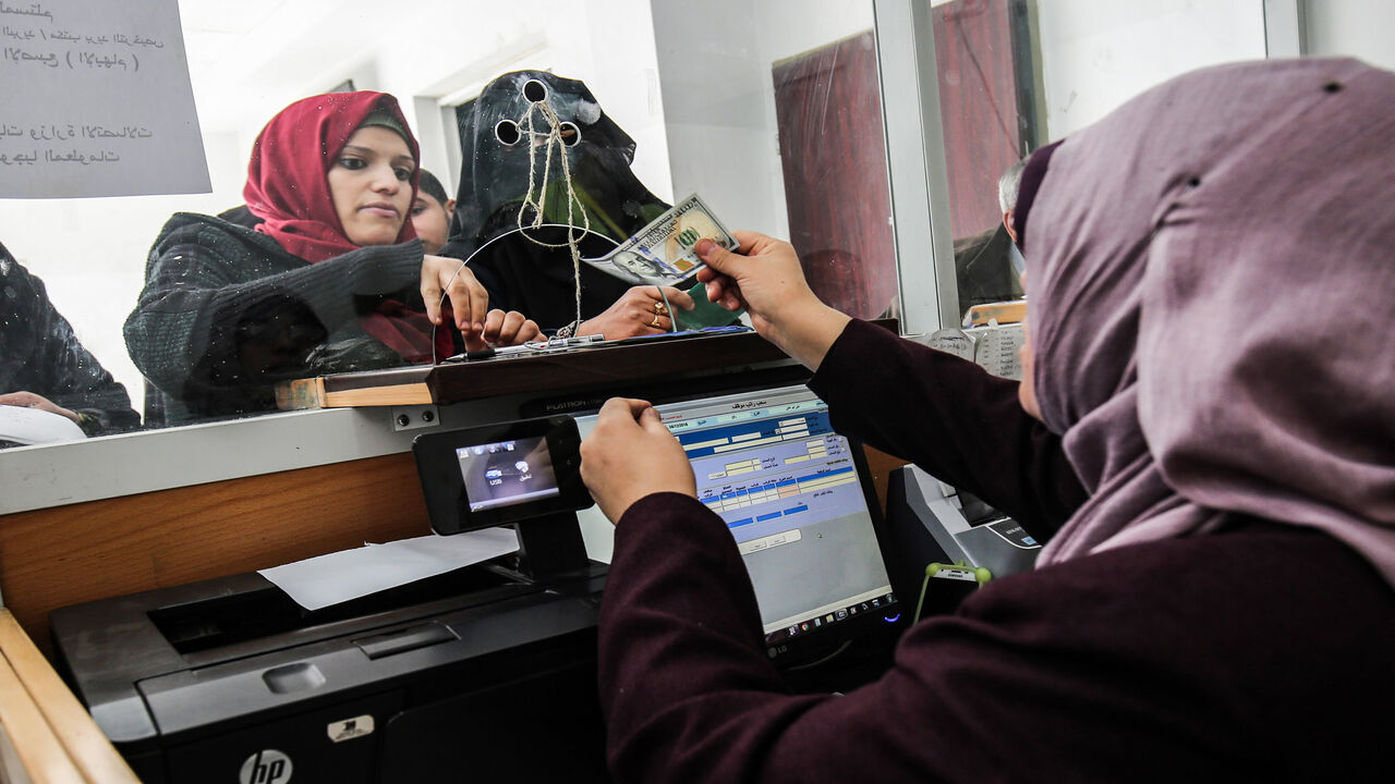 1069676316 A Palestinian government employee receives a portion her his overdue salary at a post office in Rafah in the southern Gaza Strip on December 8, 2018, after the Hamas-run finance ministry had announced that the money would be distributed over the two days, with employees receiving 50 percent of their salaries. - Employees of the Hamas administration in the Gaza Strip began collecting their salaries for a second month on December 7, after Qatar pumped more money into the territory with Israel's blessings. The