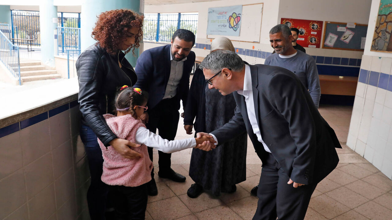 1204801257 Mtanes Shehadeh (R), an Arab-Israeli politician from the Joint List political alliance, greets a family at a polling station in the Arab city of Tamra in northern Israel on March 2, 2020. - Israelis were voting for a third time in 12 months today, with embattled Prime Minister Benjamin Netanyahu seeking to end the country's political crisis and save his career. (Photo by AHMAD GHARABLI / AFP) (Photo by AHMAD GHARABLI/AFP via Getty Images)