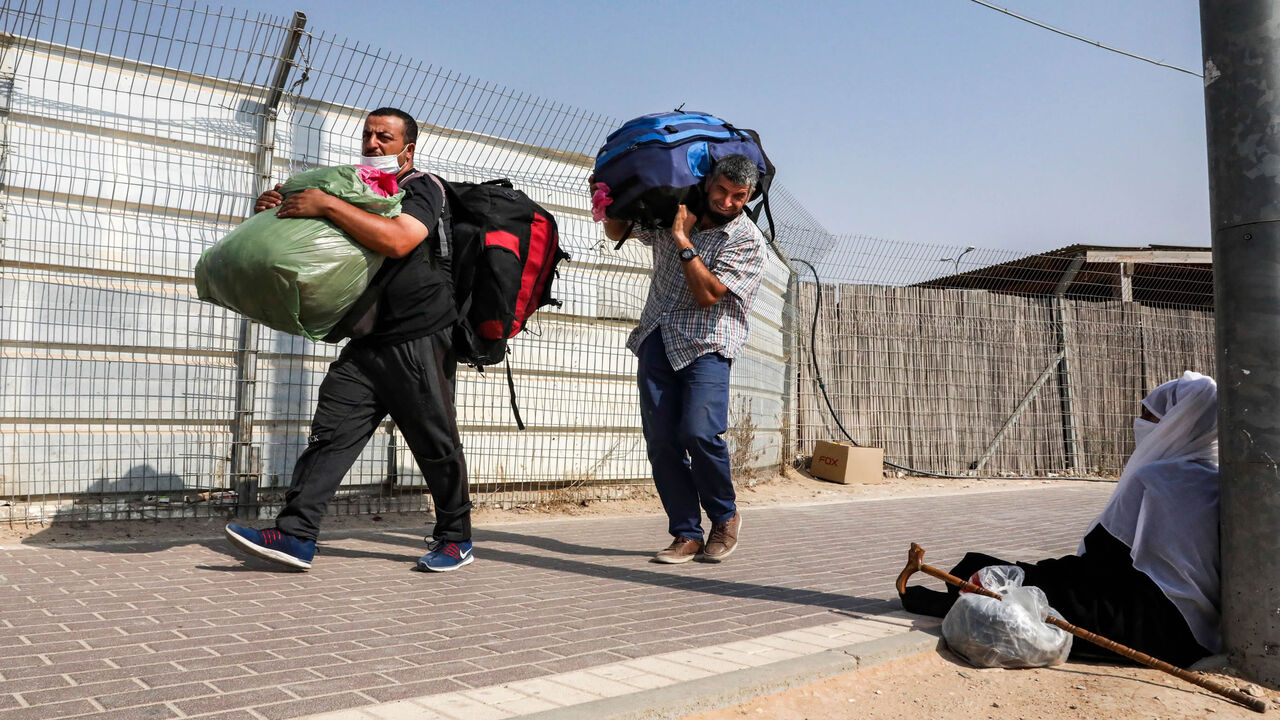 1228562463 This picture taken from the Israeli side of the Mitar checkpoint on September 17, 2020 shows Palestinian workers crossing out of Israel a day ahead of Rosh-Hashana (the Jewish New Year) and of a nationwide lockdown aimed at curbing a spike of coronavirus cases. - Israel has the world's second-highest virus infection rate after Bahrain, according to an AFP tally over the past fortnight, and on September 18 it is set to be the first country to impose a second lockdown. (Photo by HAZEM BADER / AFP) (Photo by H