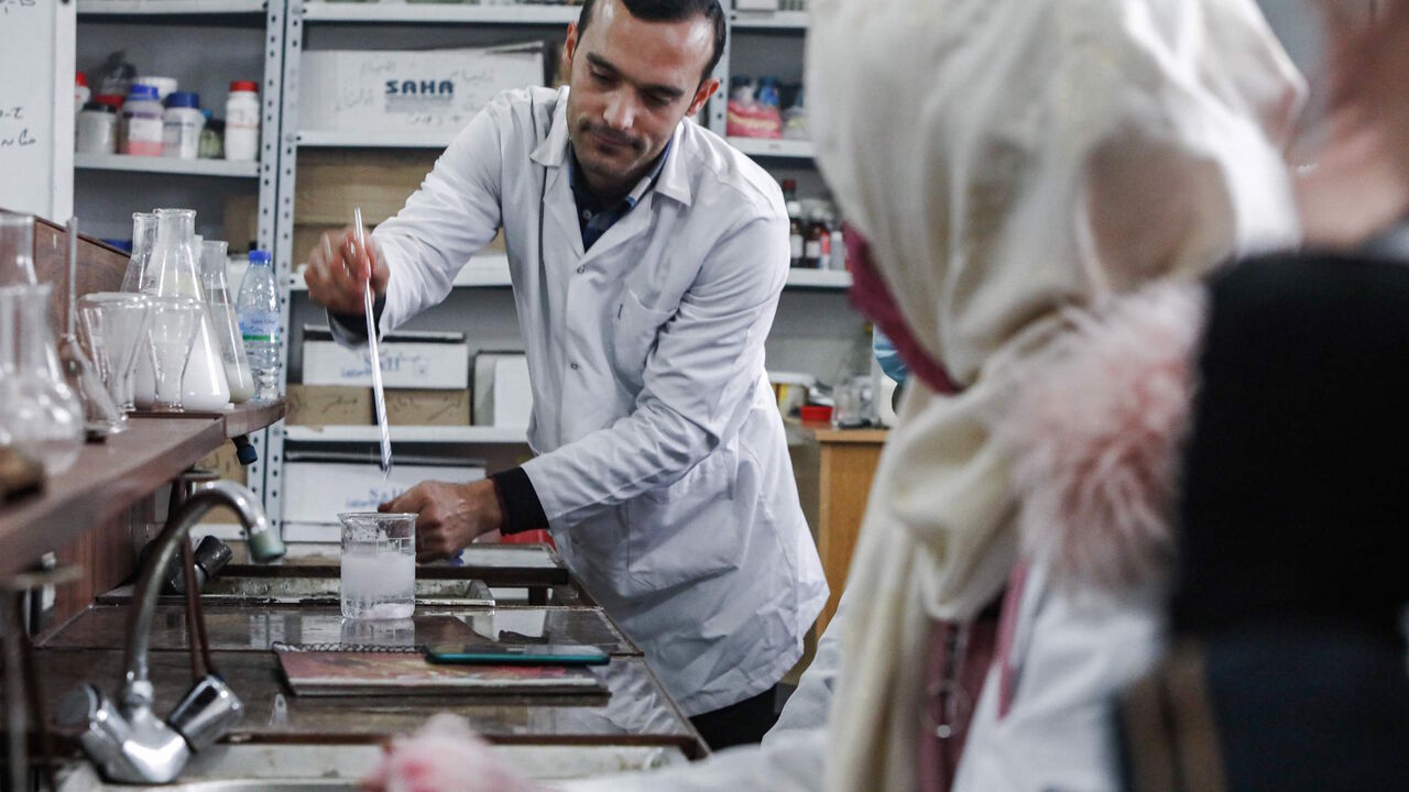 1229880670 This picture taken on November 26, 2020 shows Syrian students from the "Aleppo University in Liberated Areas", controlled by the pro-Turkey opposition, attending a tutorial at a laboratory facility in Marea in the rebel-controlled northern countryside of Syria's Aleppo province, while mask-clad due to the COVID-19 coronavirus pandemic. - The university had its first batch of 32 doctors to ever graduate after its founding in 2014, headquartered in Azaz for the past three years. Humanitarian workers fear any