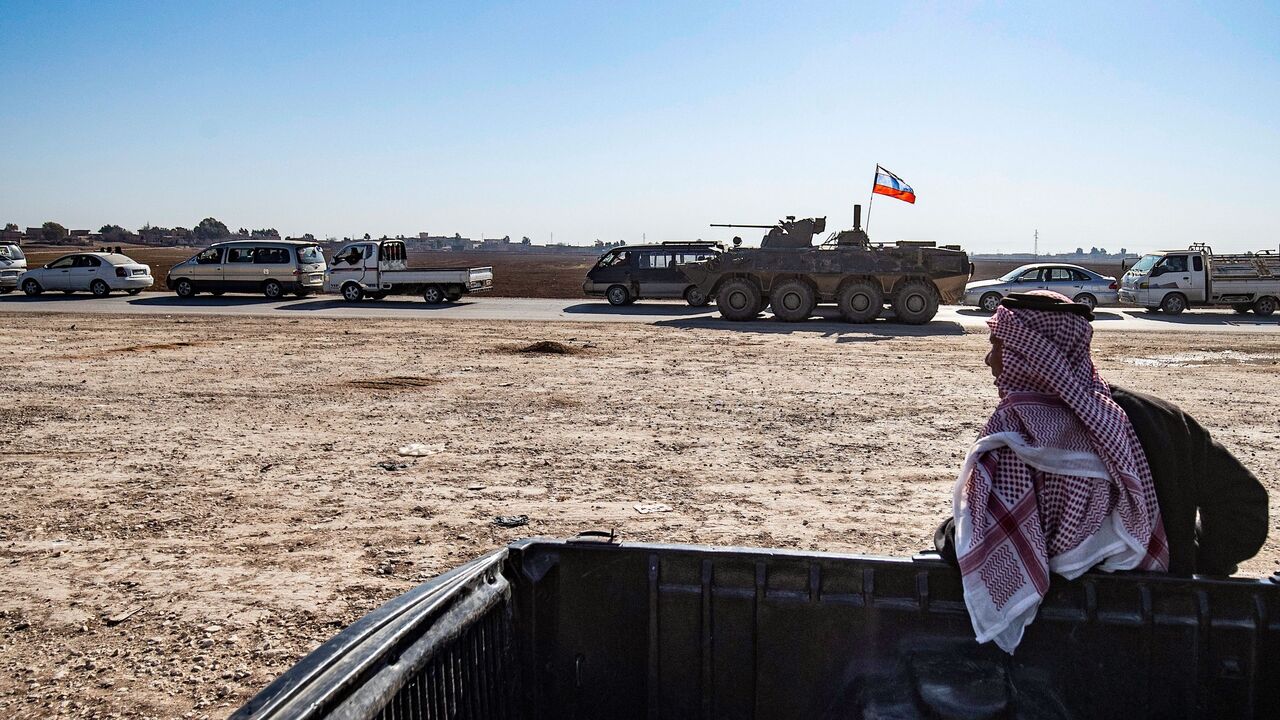 1230518605 A man watches as Russian troops escort a convoy of Syrian civilians leaving the town of Tal Tamr in the northeastern Hasakeh province, to return to their homes in the northern town of Ain Issa in the countryside of the Raqqa region, via the strategic M4 highway, on January 10, 2021. - The town of Tal Tamr is on the front line between the Syrian Democratic Forces (SDF) and the Syrian factions supported by Turkey.
Civilians stranded on both sides of the line because of heavy fighting, have been able to retur