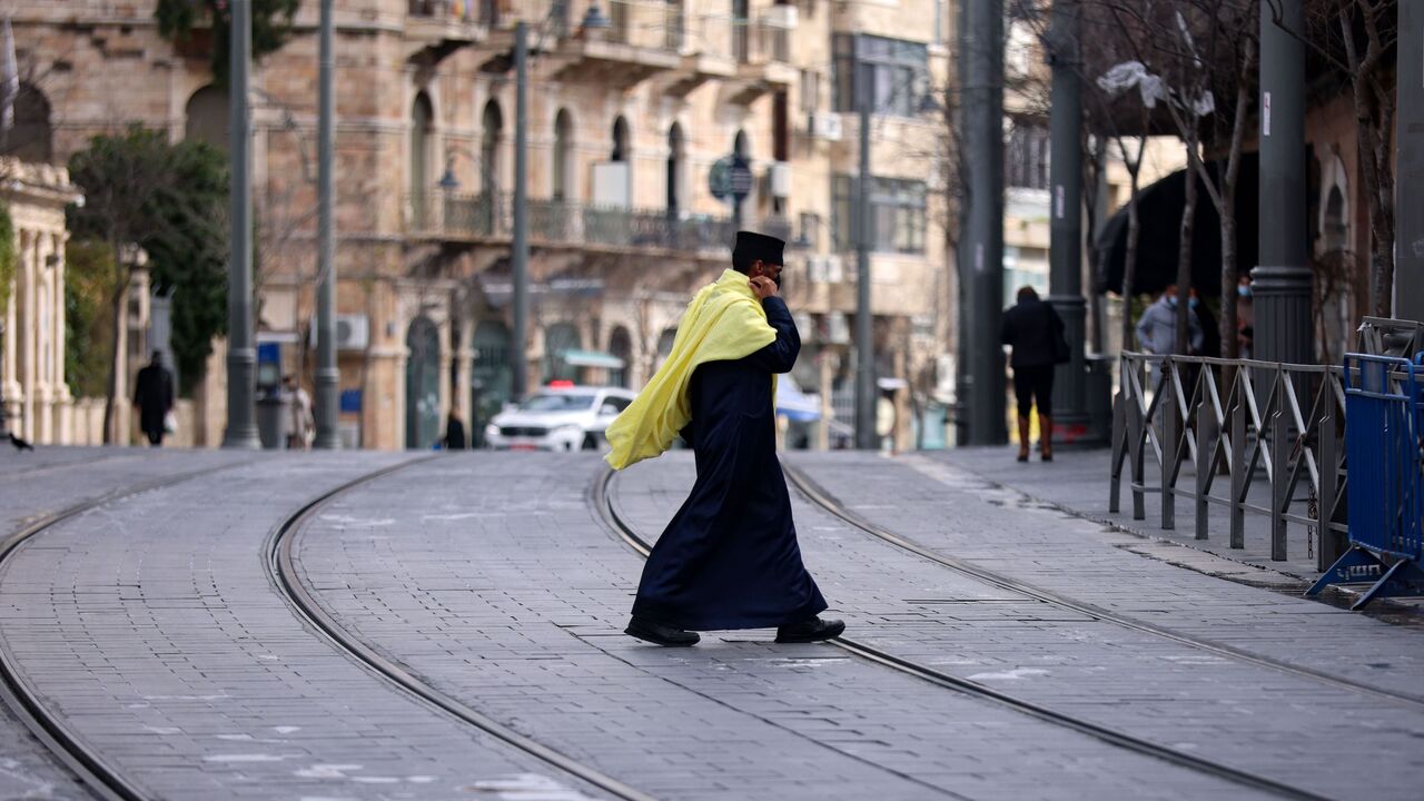 1230838339 TOPSHOT - A priest crosses a nearly deserted street during a lockdown imposed by the authorities in a bid to fight spread of the coronavirus in the centre of Jerusalem, on January 28, 2021. (Photo by Emmanuel DUNAND / AFP) (Photo by EMMANUEL DUNAND/AFP via Getty Images)