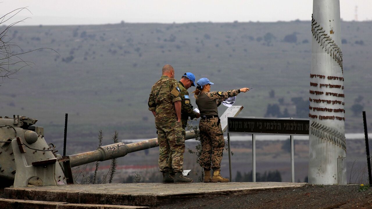 1230967320 Memebers of the United Nations Disengagement Observer Force (UNDOF) stand near an old Israeli tank as they look toward the Syrian governorate of Quneitra from the Israeli-annexed Golan Heights, on February 4, 2021. (Photo by JALAA MAREY / AFP) (Photo by JALAA MAREY/AFP via Getty Images)