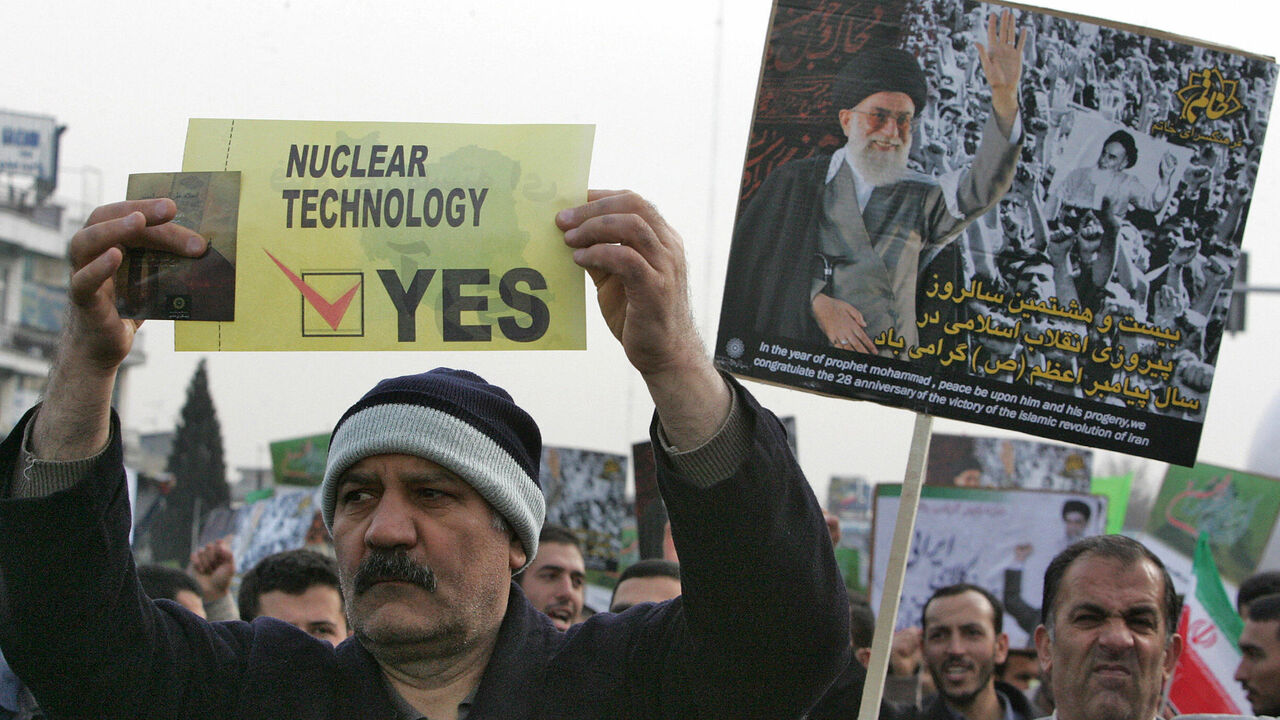 73288124 Tehran, IRAN: An Iranian man carries a placard in support of nuclear technology as another waves a portrait of Iran's supreme leader Ayatollah Ali Khamenei during a rally to mark the 28th anniversary of the Islamic revolution in Tehran 11 February 2007. Tens of thousands of Iranians took to the streets of Tehran today in an annual show of support for the Islamic revolution and to back the country's controversial nuclear programme. Throngs of people were crowding into Tehran's massive Azadi square, where Ira
