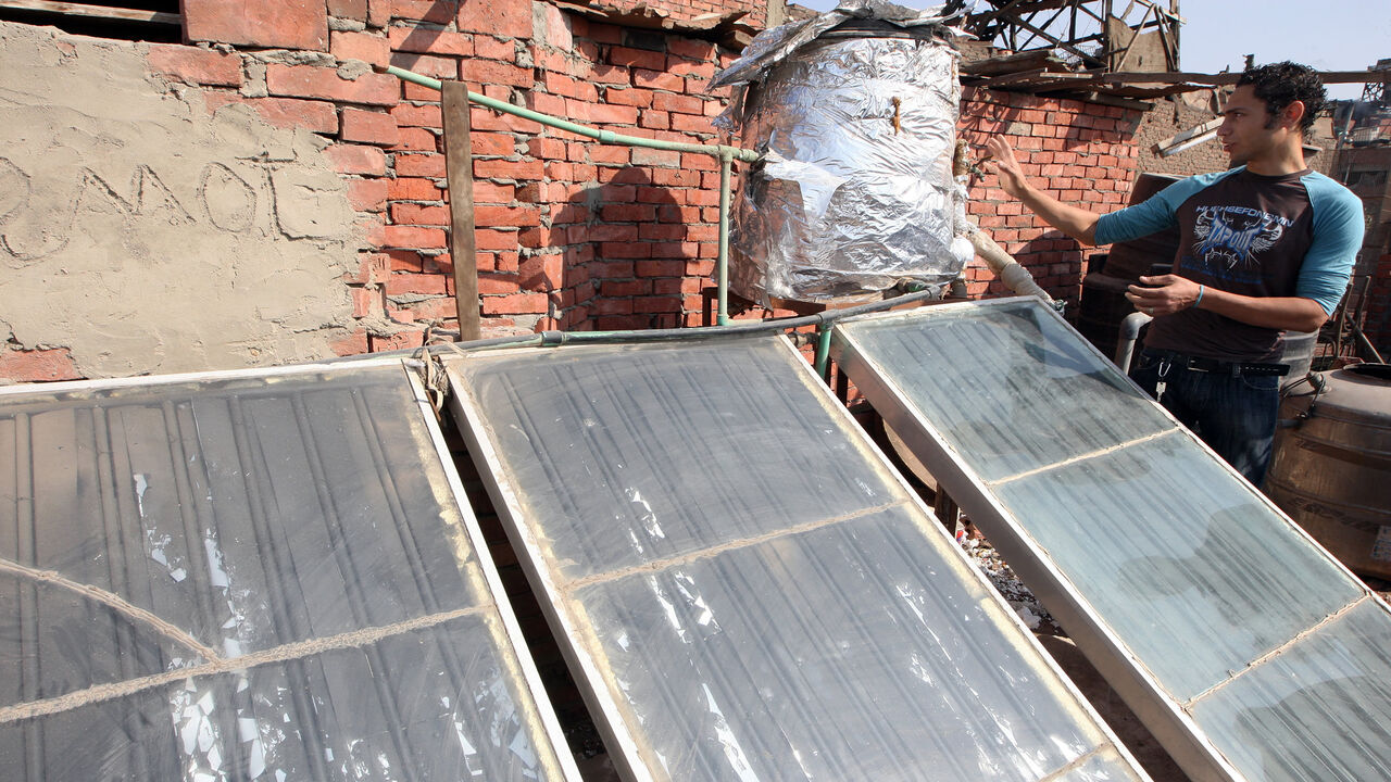 94984738 TO GO WITH AFP STORY BY EMMY VARLEY Egyptian Hanna Fathy, an advocate of a biogas project in Egypt, inspects a solar panel installation on his rooftop in Cairo on November 20, 2009. In an attempt to help curb the city's stifling pollution and meet their energy needs too, a few Cairo families have begun to recycle waste -- now that the nation's pigs are gone -- by generating biogas from rubbish. AFP PHOTO/CRIS BOURONCLE (Photo credit should read CRIS BOURONCLE/AFP via Getty Images)
