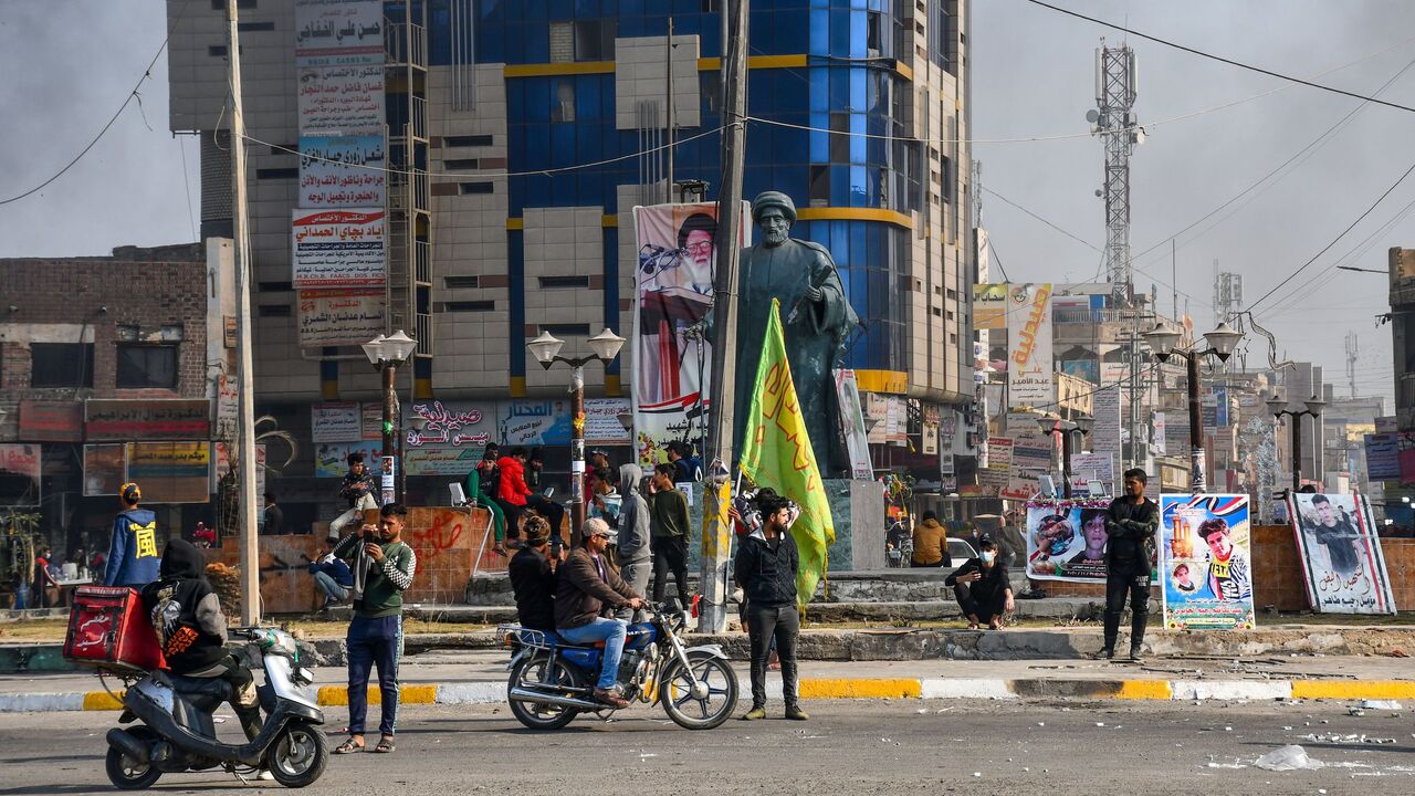 1230518356 Protesters are pictured in a square as smoke billows following clashes between Iraqi police forces and anti-government protesters in Nasiriyah in southern Iraq on January 10, 2021. - A policeman was killed today in Iraq, the army said, as security forces fired to disperse a third consecutive day of protests in the city of Nasiriyah, according to medics. (Photo by Asaad NIAZI / AFP) (Photo by ASAAD NIAZI/AFP via Getty Images)
