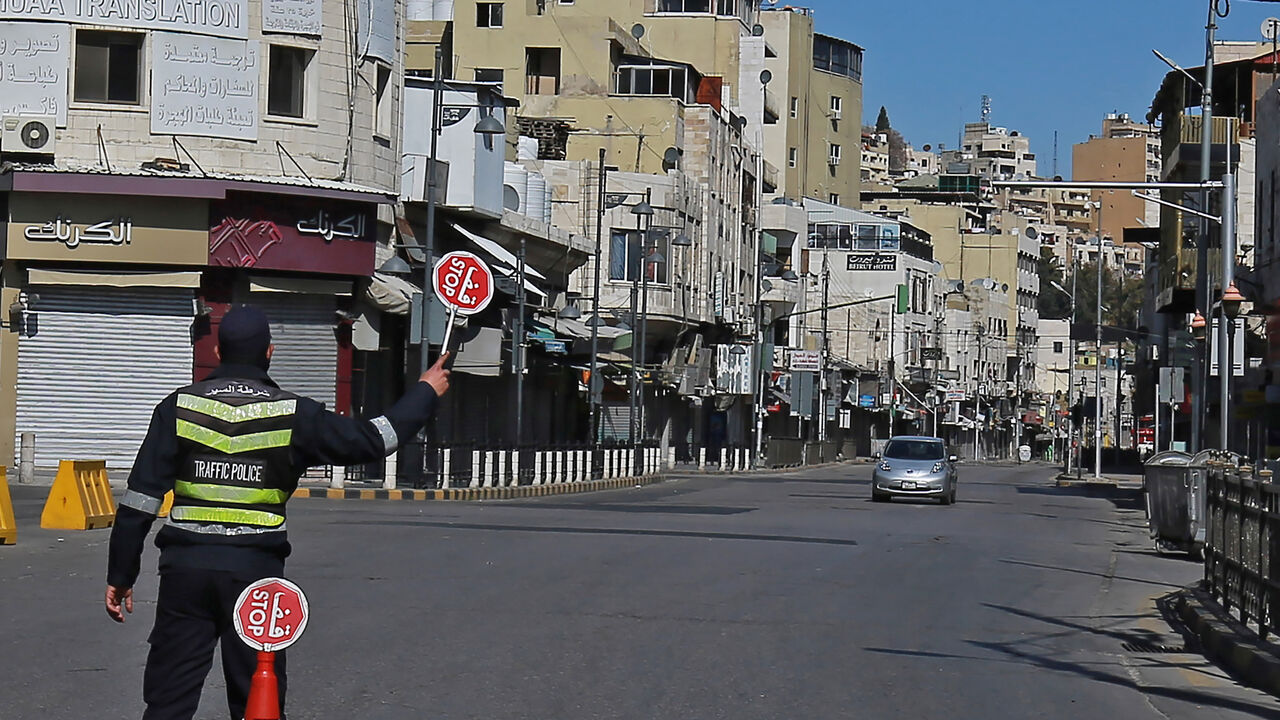 1231393841 A policeman holds a stop sign in an almost deserted avenue in the Jordanian capital Amman, during a lockdown due to the coronavirus panemic, on February 26, 2021. (Photo by Khalil MAZRAAWI / AFP) (Photo by KHALIL MAZRAAWI/AFP via Getty Images)