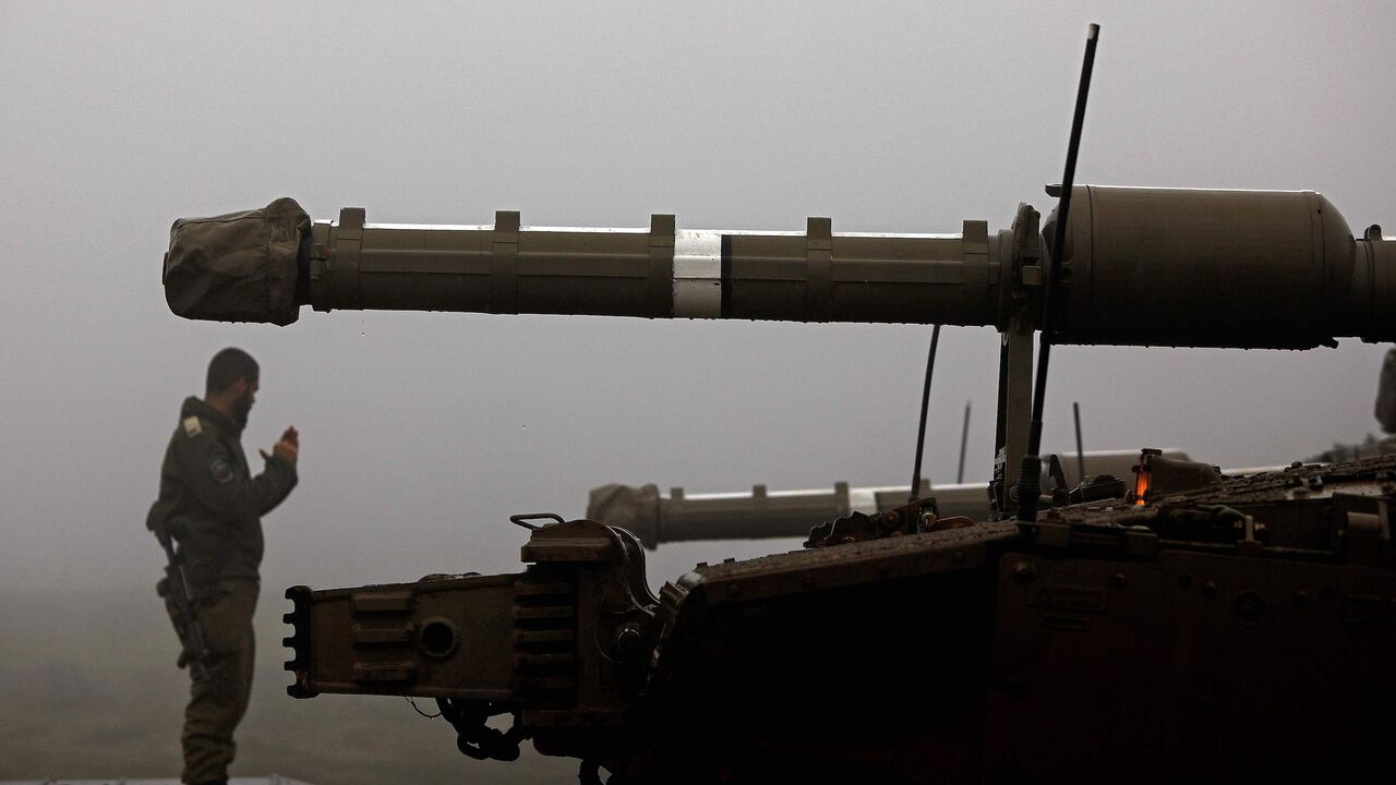1231454338 An Israeli soldier stands near a parked Merkava Mark IV battle tank near Moshav Alonei HaBashan in the Israeli-annexed Golan Heights on March 1, 2021. (Photo by Jalaa MAREY / AFP) (Photo by JALAA MAREY/AFP via Getty Images)