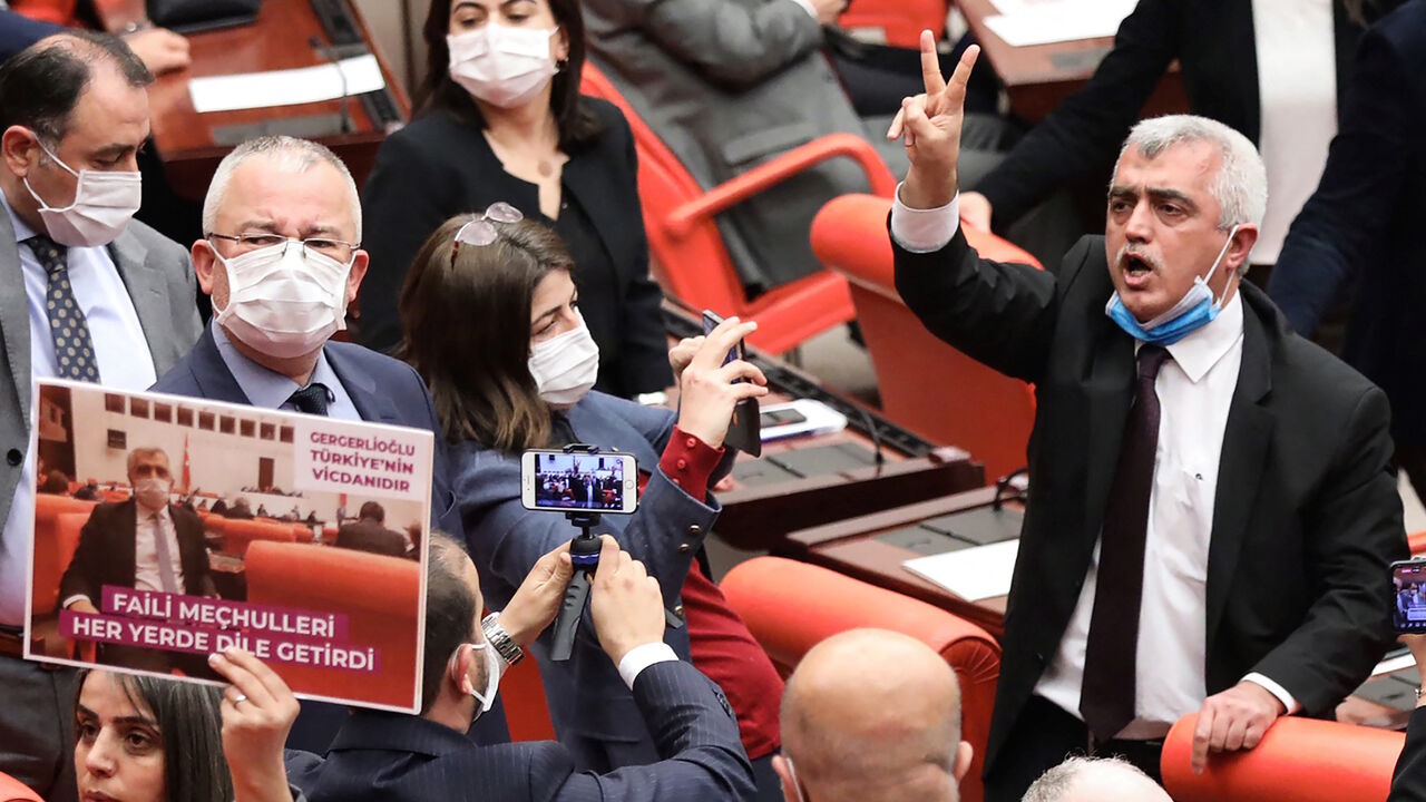 1231766217 Turkish member of Parliament for the left wing political party Peoples' Democratic Party Omer Faruk Gergerlioglu (C) reacts as he is surrounded by MPs applauding and brandishing placards after he was dismissed following a vote at the Turkish Parliament in Ankara, on March 17, 2021. (Photo by Adem ALTAN / AFP) (Photo by ADEM ALTAN/AFP via Getty Images)