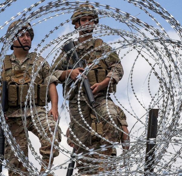 Lebanese army soldiers stand behind barbed wire fence demarcating the Blue Line, near the village of Kfar Shuba, southern Lebanon, June 11, 2023. 