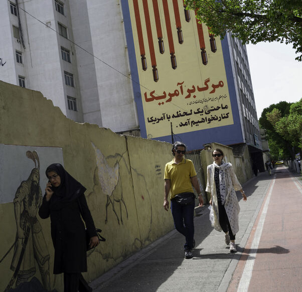 Iranians pass by the recently repainted, famous anti-American mural that depics the US flag with bombs and skulls in Tehran, Iran on April 10, 2025, two days before the first round of indirect nuclear negotiations with President Trump's administration hosted and mediated by Oman. (Photo by Mohammadali Najib / Middle East Images / Middle East Images via AFP) (Photo by MOHAMMADALI NAJIB/Middle East Images/AFP via Getty Images)