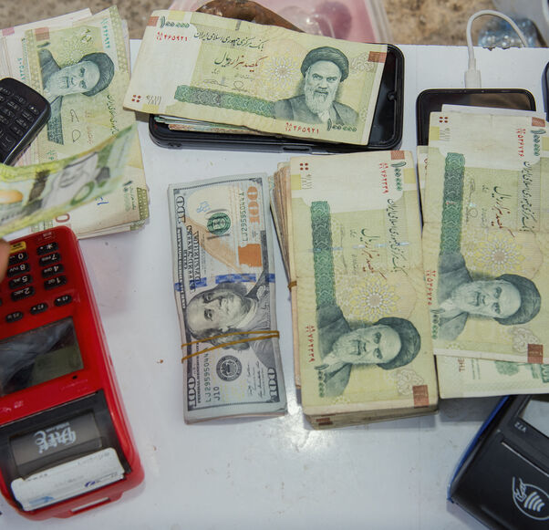 Stacks of Iranian rials and US dollars sit counted on a table in an unofficial currency exchange shop, Tehran, Iran, Aug. 6, 2025.