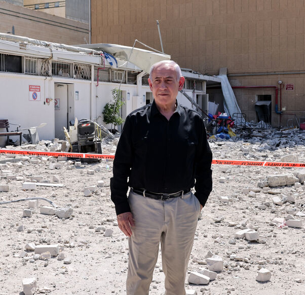 Israeli Prime Minister Benjamin Netanyahu stands amid debris outside the Soroka Hospital in the southern city of Beersheba, after it was hit by a missile fired from Iran on June 19, 2025. Israel's defence minister warned that Iran's supreme leader "can no longer be allowed to exist" after a hospital was hit in an Iranian missile strike on June 19, spiking tensions in the week-old war. (Photo by Marc Israel SELLEM / POOL / AFP) (Photo by MARC ISRAEL SELLEM/POOL/AFP via Getty Images)