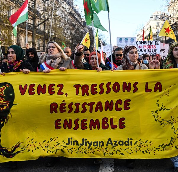Protesters hold a banner reading "Come and weave resistance together" and "Women, life, freedom." 